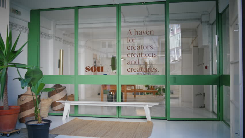 Woman entering store gallery on weekend. Young visitor walking city building opening door to art design shop. Casual girl tourist go showroom home decor space. Beautiful urban entrance facade concept