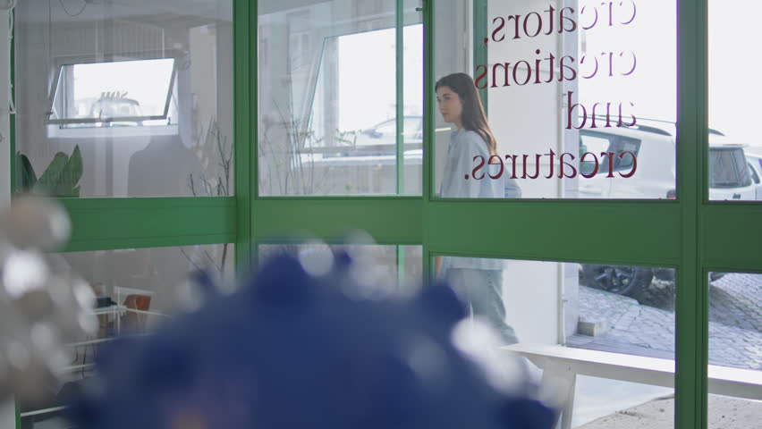 Woman entering store door on weekend. Closeup smiling customer looking goods selecting items. Beautiful brunette visiting walking in art showroom gallery. Thoughtful young designer checking home decor
