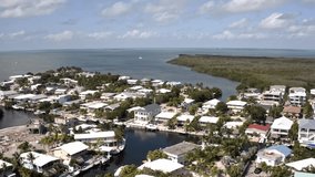 Aerial drone Footage in Florida, USA, commercial area, luxury houses, buildings and mansions, abundant tropical vegetation around, blue sky and Ocean.