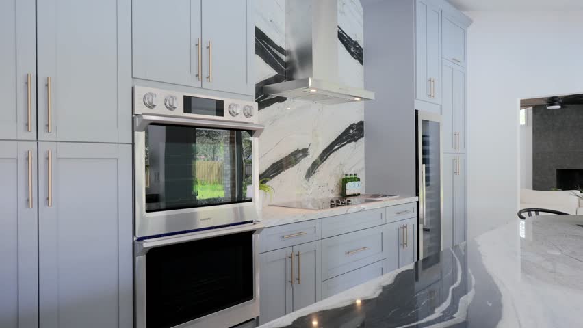 Luxurious bright matte kitchen with white cabinetry and built-in modern appliances from stainless steel. Glossy quartz splashback and island with black pattern Royalty-Free Stock Footage #1108819553