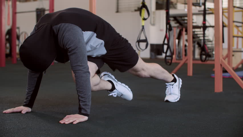 Male athlete doing mountain climbing exercise. Young man is doing physical training at gym. He is wearing sportswear at healthcare center while working out.