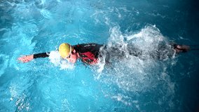 Underwater view of professional swimmer training in swimming pool, 4k 120 fps super slow motion raw video. Triathlete swim in black wetsuit 