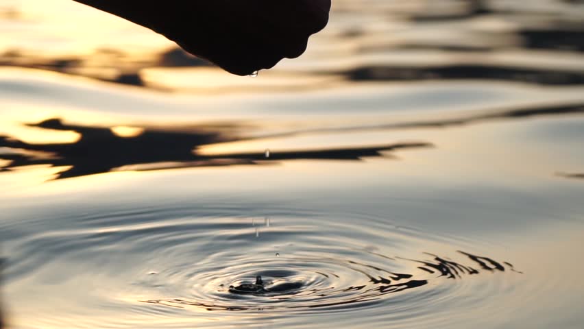 Woman hand sea. Close-up Happy Woman gently caresses water surface at sunset in a warm, golden evening by the sea or lake. Slow-motion Concept of happiness, boat life and holidays in exotic places
