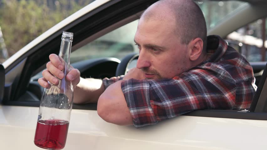 A depressed man drinks alcohol while driving a car. The risk of driving while intoxicated. Car accident. Illegal drunk driving. Royalty-Free Stock Footage #1108828085