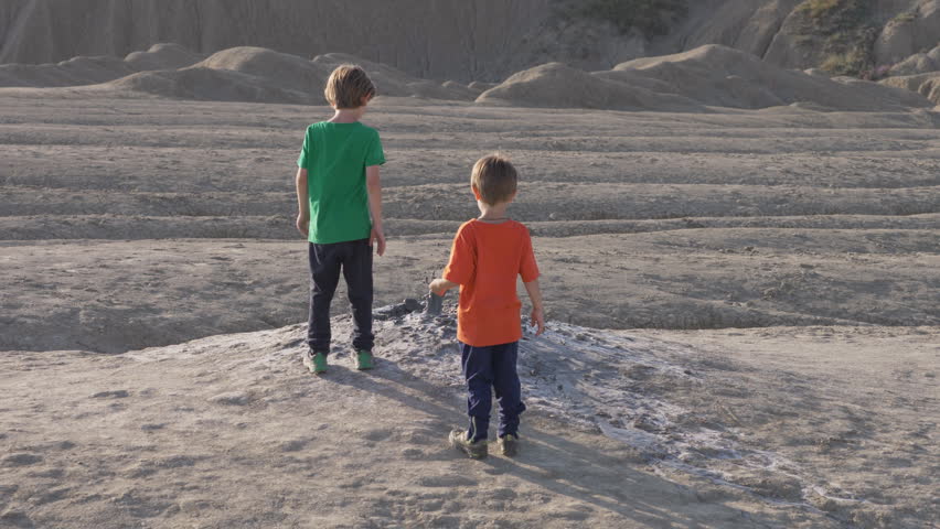 Kids playing by throwing rocks in the mud volcano