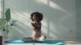 Young pregnant African woman practicing yoga meditation on a mat near a window in morning sunlight. Concept of prenatal fitness, maternity wellness, and relaxation. - Powered by Shutterstock - Get 15% off with code: PIKWIZARD15