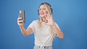 Young blonde woman smiling confident having video call over isolated blue background
