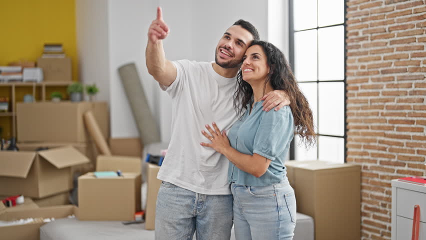 Man and woman couple hugging each other looking around at new home