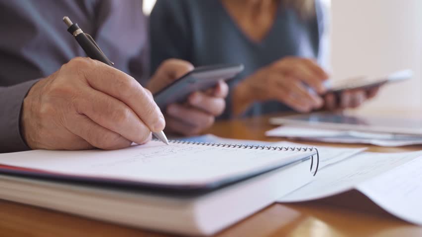 Close up of hand writing numbers and calculating taxes and budget - Powered by Shutterstock - Get 15% off with code: PIKWIZARD15