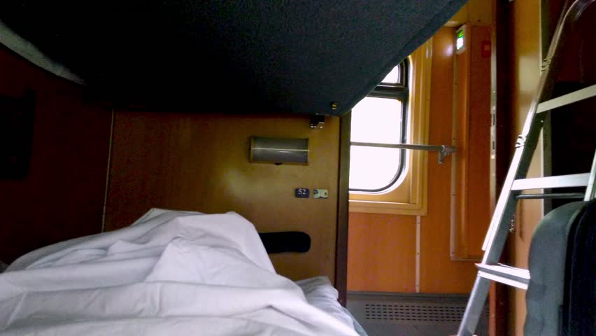 Sleep on the night train. Lie down shelf. The passenger is traveling. Recumbent seat compartment in the train Warsaw - Kyiv. View from inside Ukrainian high speed train.