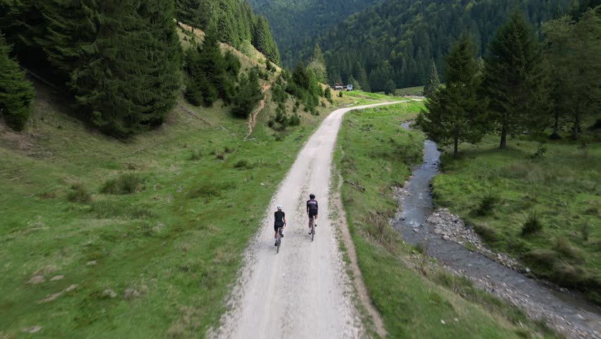 Top view of cyclists are riding gravel bikes in the scenic beauty of the mountains.Cycling on gravel roads or off-road.Active adventures and the concept of travel by bike.Gravel bike riding in nature. Royalty-Free Stock Footage #1108834513