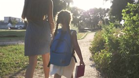 Mom and daughter go to school. Happy family in park. Mom and happy daughter go to school. Schoolgirl with a backpack holds mom hand. Schoolgirl in park goes to school. Family goes to school - Powered by Shutterstock - Get 15% off with code: PIKWIZARD15