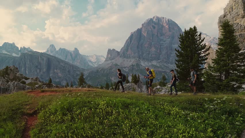 Aerial close up view group of friends with backpacks hiking trail path and trekking Dolomites mountain. Group of friends summer adventure journey in nature. Travel exploring Alps, Dolomites, Italy