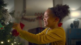 Excited girl at home hanging Christmas bauble decoration on tree - shot in slow motion - Powered by Shutterstock - Get 15% off with code: PIKWIZARD15