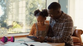 Father at home helping daughter in lounge as she does homework using digital tablet - shot in slow motion - Powered by Shutterstock - Get 15% off with code: PIKWIZARD15
