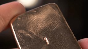 after grinding and polishing, the worker checks after casting a homemade gold bar made in artisanal conditions, looking at its texture and reflections with iridescence - Powered by Shutterstock - Get 15% off with code: PIKWIZARD15