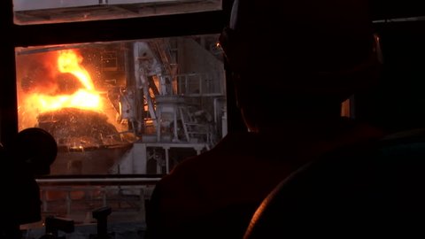 silhouette of a man in a helmet on a background of working oxygen furnace