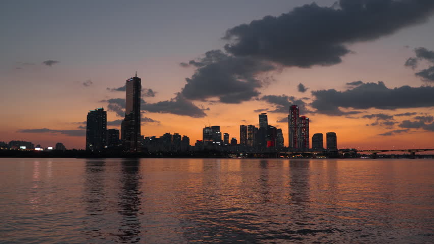 Silhouetted Yeouido Island Bussines District and 63 Building Skyscraper in Yeongdeungpo-gu During Colorful Sunset with Dramaic Sky, View form Han River Park Waterfront, Iconic Seoul Skyline
