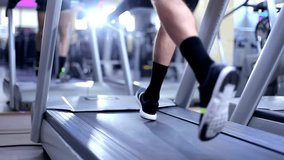 A woman in black trousers runs on a treadmill in the gym Classes on the Running machine help not only to achieve in a short time the ideal forms