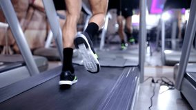 Close up of two people feet running on treadmill in gym low angle view sport club Slow motion Close up