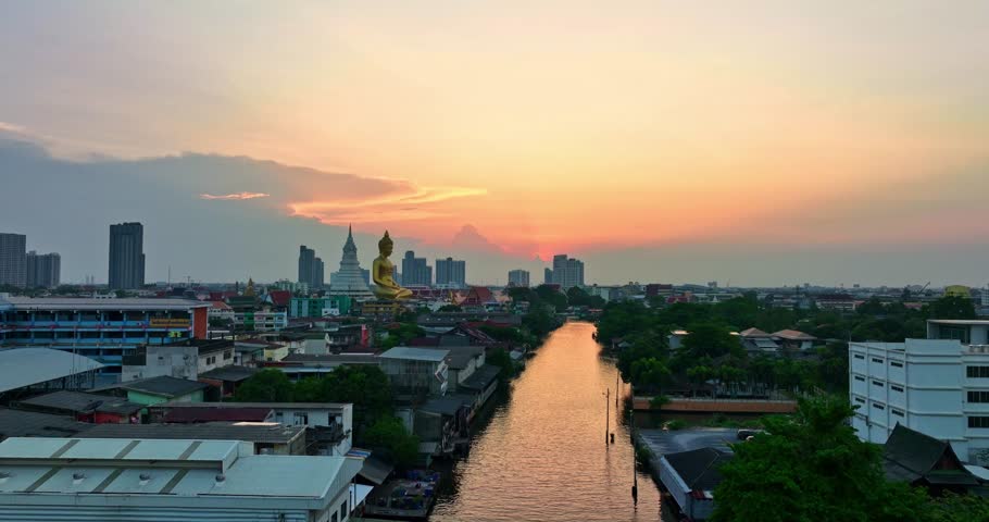 aerial view golden big Buddha Wat Paknam Phasi Charoen beside a small canal.
scenery sky of sunset at golden big Buddha popular landmark in Bangkok Thailand. 
beautiful red cloud over bangkok city.