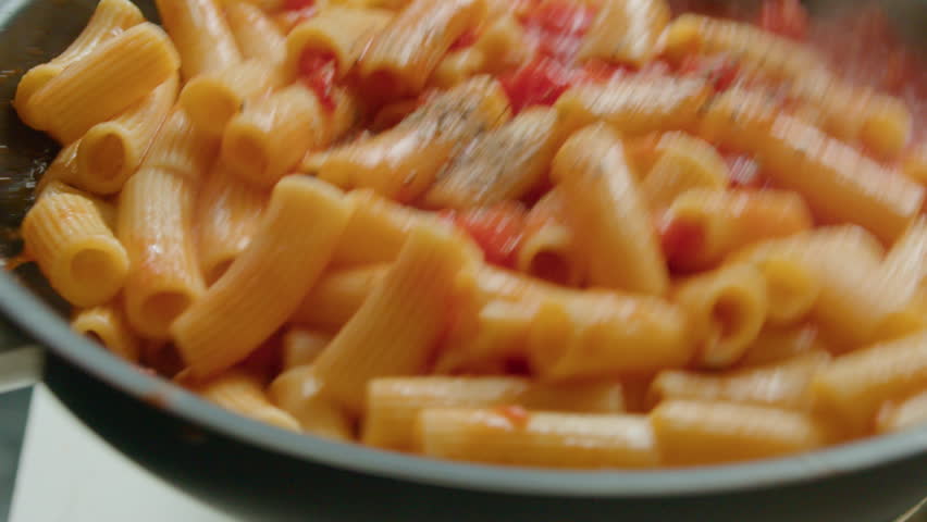 Extreme close-up shot of cooking rigatoni with tomato sauce and spices, tossing pasta in a skillet and mixing ingredients Royalty-Free Stock Footage #1108855105