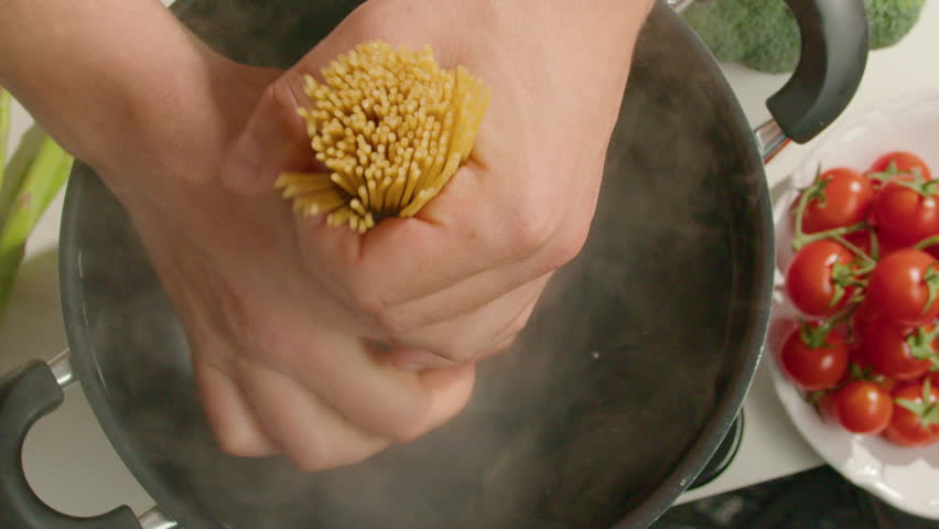 Male hands putting a bunch of spaghetti into a cooking pot with boiling water while cooking pasta at home. Close-up view, top down shot Royalty-Free Stock Footage #1108855227
