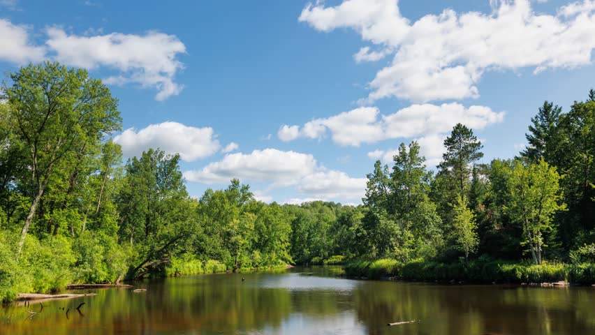 Time lapse of the clouds moving above Kettle River surrounded by forest in Minnesota.
