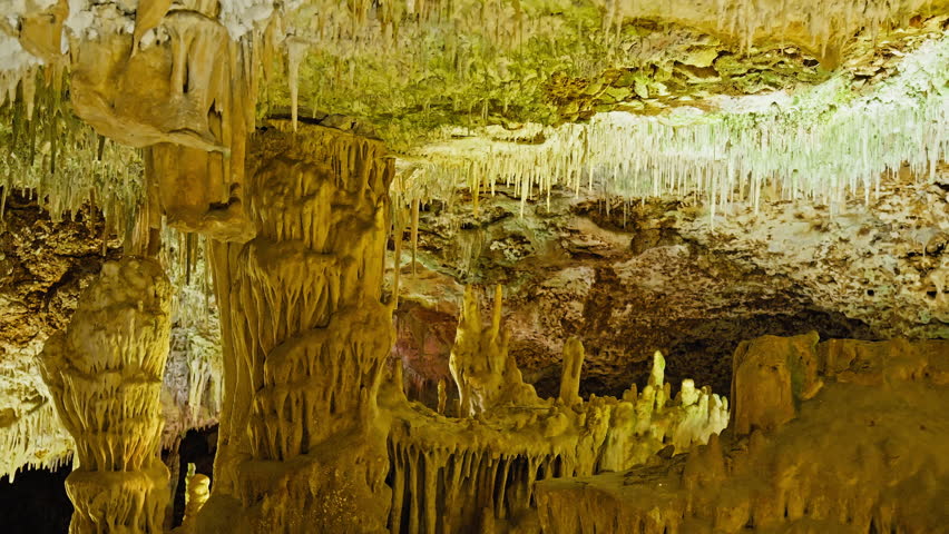 Underground cave with distinct rocky formations of stalactites and stalagmites. A colourful natural scenery in a cave with ancient cavities formed of carbonate limestone rocks in Mallorca, Spain. Royalty-Free Stock Footage #1108859019