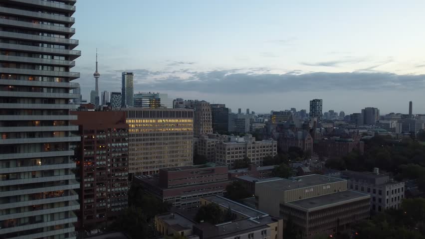 Evening rise-up aerial shot of downtown Toronto. Drone flying over the financial district while showing the cityscape and the CN tower in the distance. Modern high-rises combined with old architecture