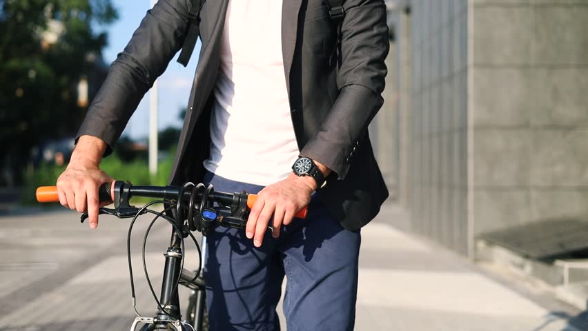 Businessman in formal clothes pushing his bicycle across traffic jam in rush hour, young professional man enjoyed walking on street in the city, away from traffic