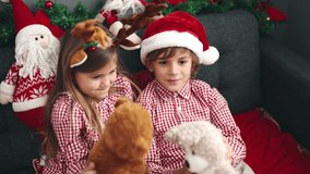 Brother and sister playing with teddy bears sitting on sofa by christmas decoration at home - Powered by Shutterstock - Get 15% off with code: PIKWIZARD15
