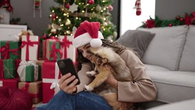 Young hispanic woman with dog having video call celebrating christmas at home