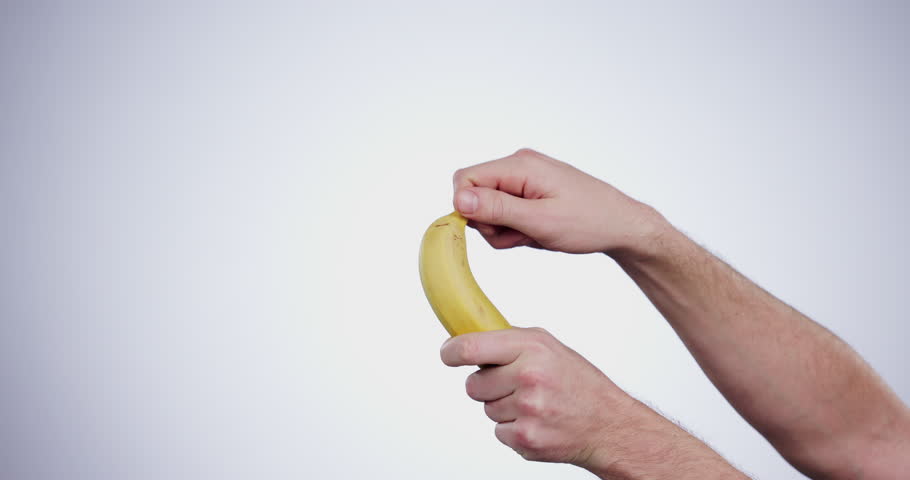 Hands, diet and a person peeling a banana in studio on a gray background closeup for health or nutrition. Fruit, food or healthy eating and a vegan adult with fresh produce for hunger or mockup space
