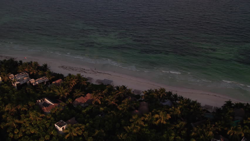 Aerial shot of rolling waves in a white sand beach with palm trees and cabins and huts at night in Tulum, Mexico Royalty-Free Stock Footage #1108882231