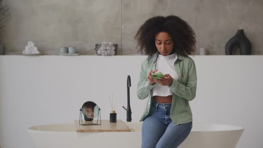 Black Woman Reading Bad News on Cell Phone Sitting at Home. Upset female using smartphone. Royalty-Free Stock Footage #1108884693