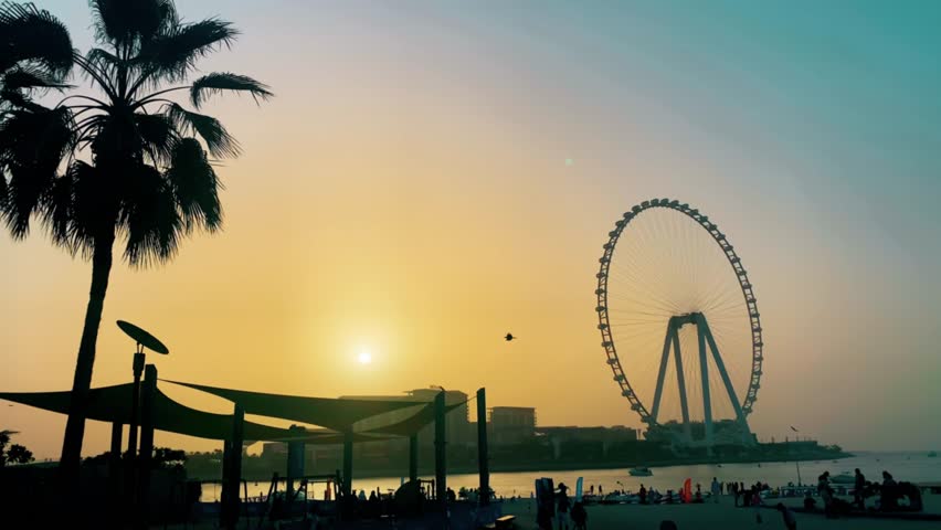 Beautiful landscape of the Persian Gulf in Dubai at sunset. Silhouette large Ferris wheel. Concept of travel to the united arab emirates.