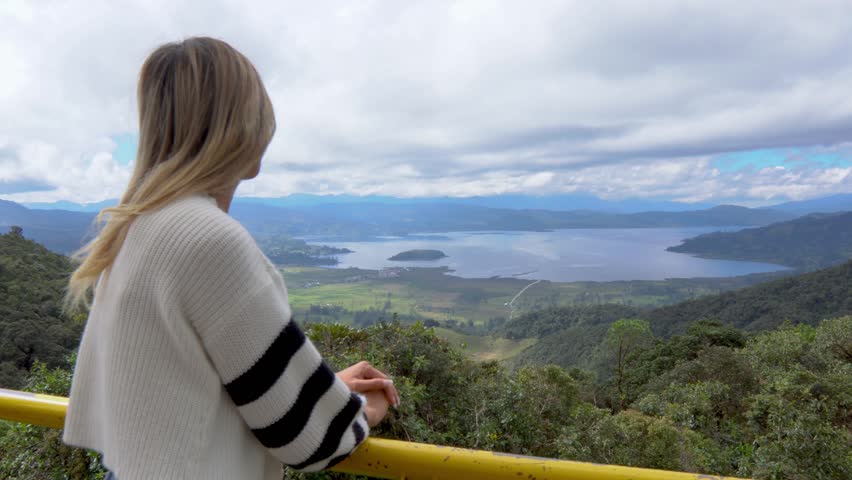 WOMAN LOOKING AT LA COCHA LAGOON OR LAKE GUAMUEZ PASTO NARIÑO. COLOMBIAN LANDSCAPE