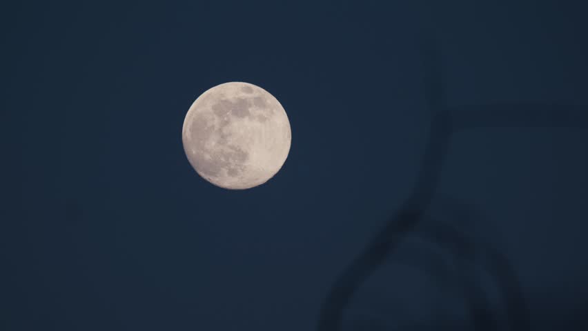 The full moon shining brightly in the dark blue sky during the nighttime