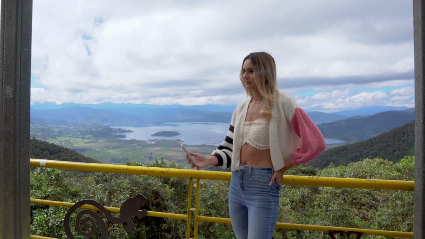 WOMAN MAKING A VIDEO CALL WITH CELL PHONE ON THE INTERNET. LAKE GUAMUEZ OR LAGOON DE LA COCHA PASTO NARIÑO
