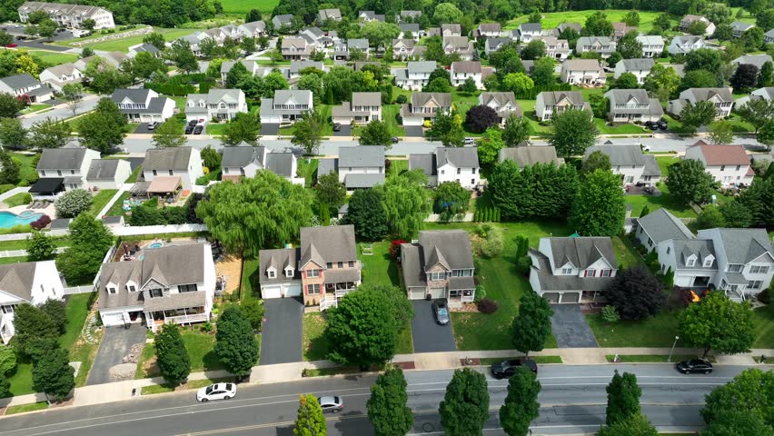 Large American neighborhood. Aerial truck shot of houses and homes in housing development lined with trees during summer.