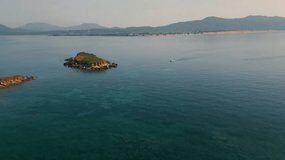 A aerial Video of a Boat on its way to a small island in front of the shore at Corfu in Greece. The Video was taken in the morning so the water is still flat and blue.