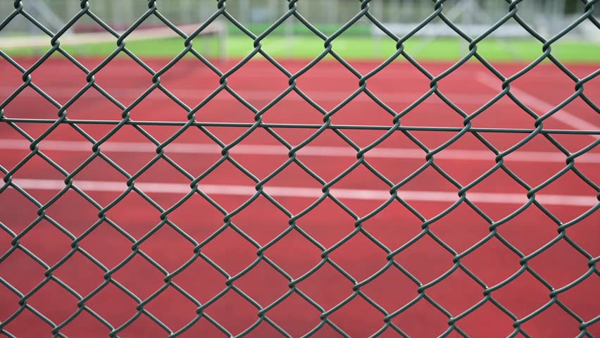 Through the chain-link fence, a blurred tennis court beckons, enticing players to the game and sporting competition. Royalty-Free Stock Footage #1108903217