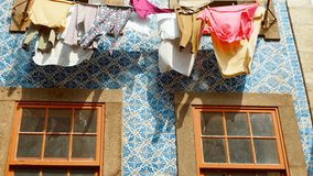 Colorful clothes hang outside a charming tiled house, adding local flair to the scenic streets of Porto, Portugal, famous for Port wine
