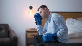 Side view focused young businessman in elegant suit and boxing gloves thinking looking away. Medium shot concentrated Caucasian stressed man planning startup in bedroom at home - Powered by Shutterstock - Get 15% off with code: PIKWIZARD15