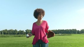 Active concentrated pretty black female pitcher with baseball glove and ball in casual clothes preparing for pitch, looking with determined expression while playing game on green field in public park. - Powered by Shutterstock - Get 15% off with code: PIKWIZARD15