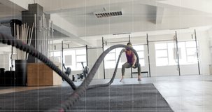 Animation of graph processing data over caucasian woman cross training with battle ropes at gym. Fitness, exercise, strength, data, digital interface and technology digitally generated video.