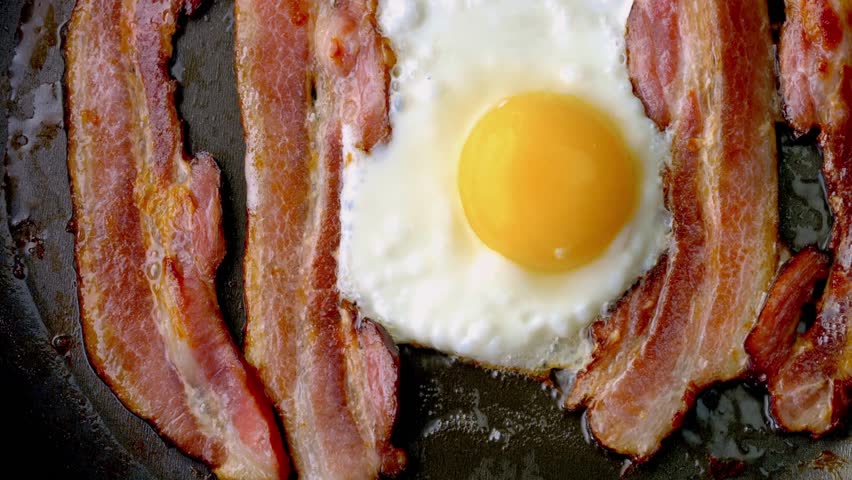  Sizzle and Sunshine: Close-Up of Cooking Bacon and Egg in a Pan in 4K Video Royalty-Free Stock Footage #1108917589