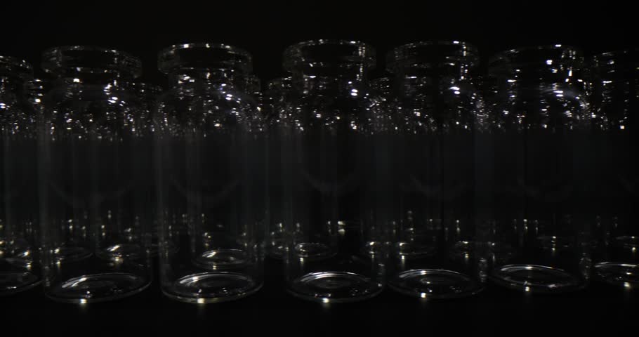 Empty glass vials in rows used for vaccine production and packaging on black background. Professional glassware for medical purposes and laboratory investigations | Shutterstock HD Video #1108919287