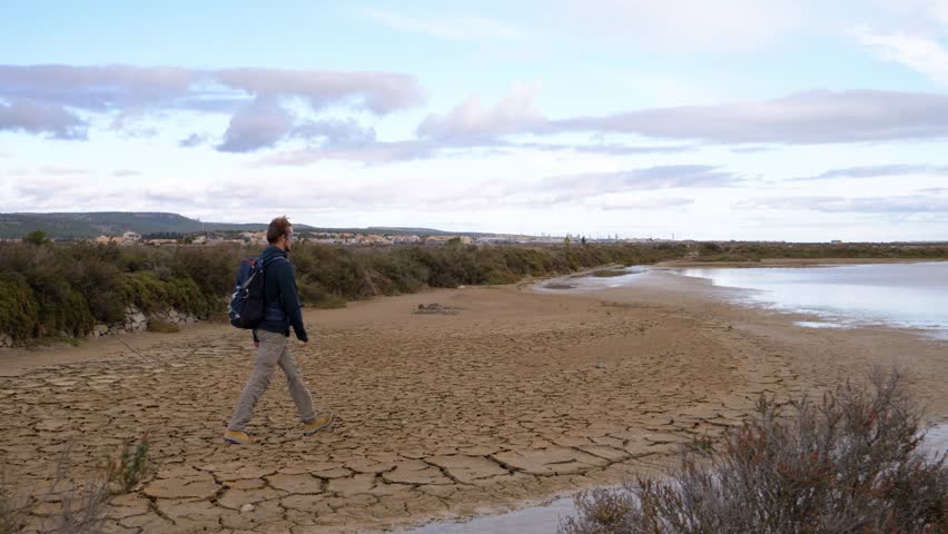 slow motion revealing shot of a man walking along the edges of the Sete salt flats